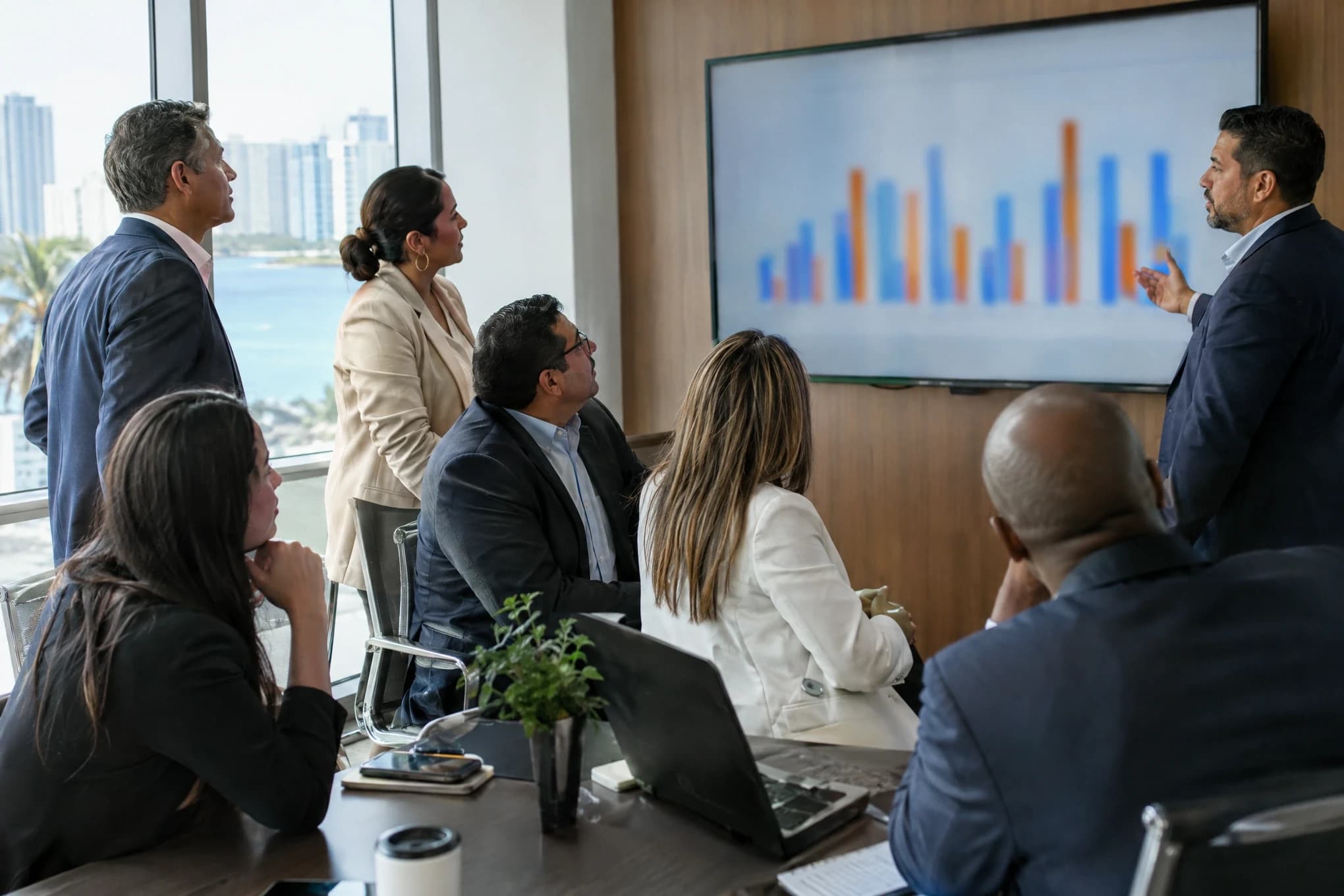 Directivos de una empresa establecida revisan una pantalla con gráficos de barras desenfocados en una sala de reuniones