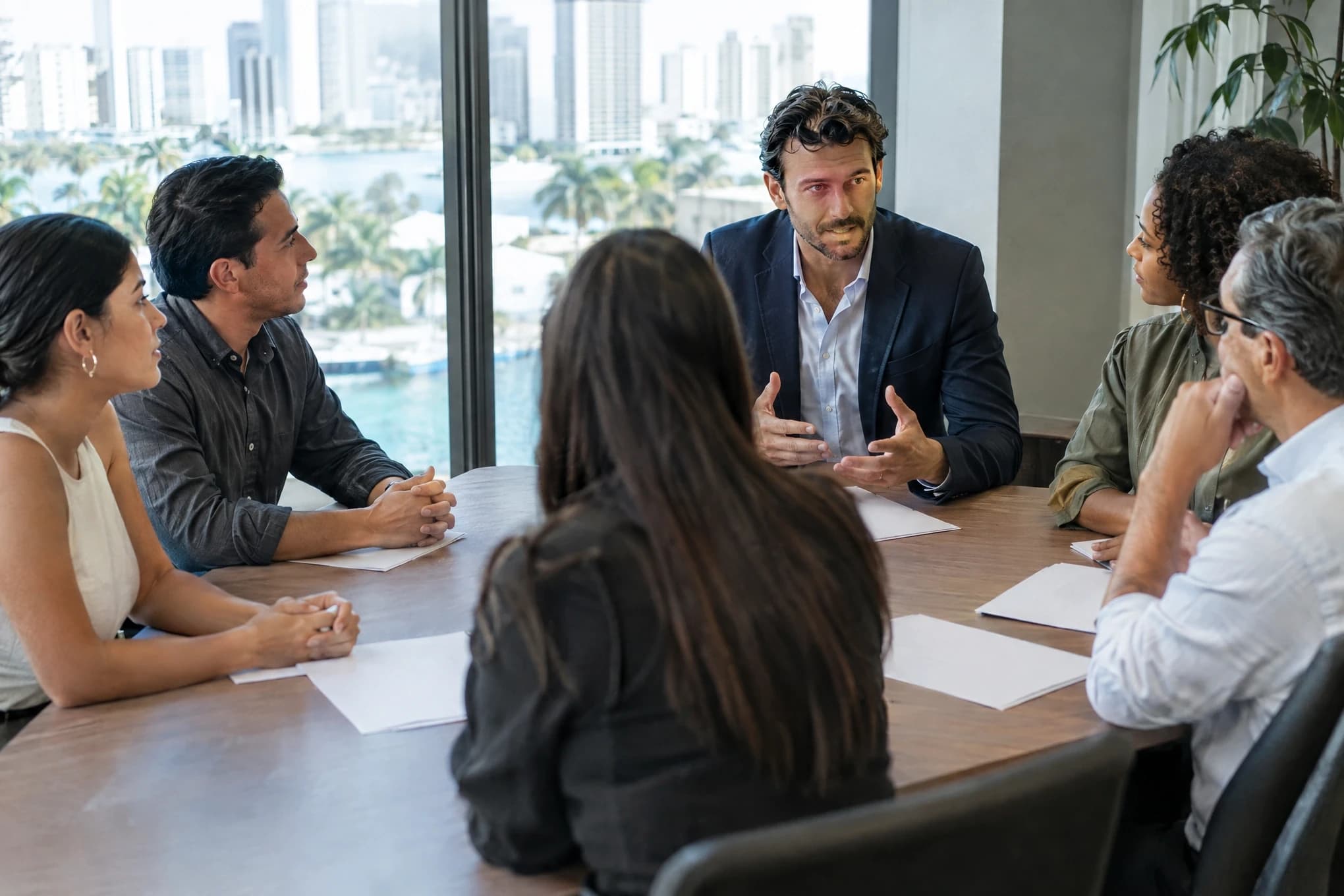 An agency director calmly explains a plan to a client company's five-person team
