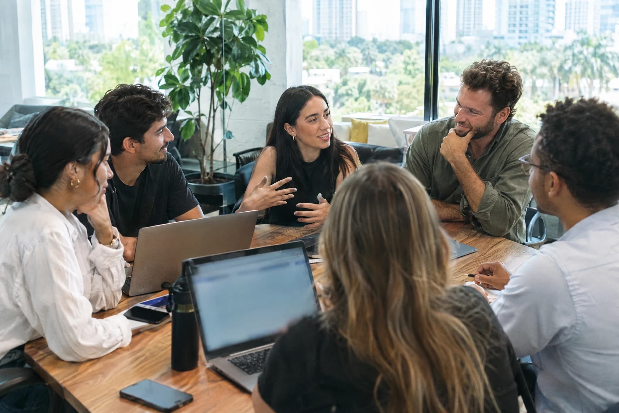Los fundadores y cinco empleados de una empresa joven planifican juntos alrededor de una mesa en su oficina
