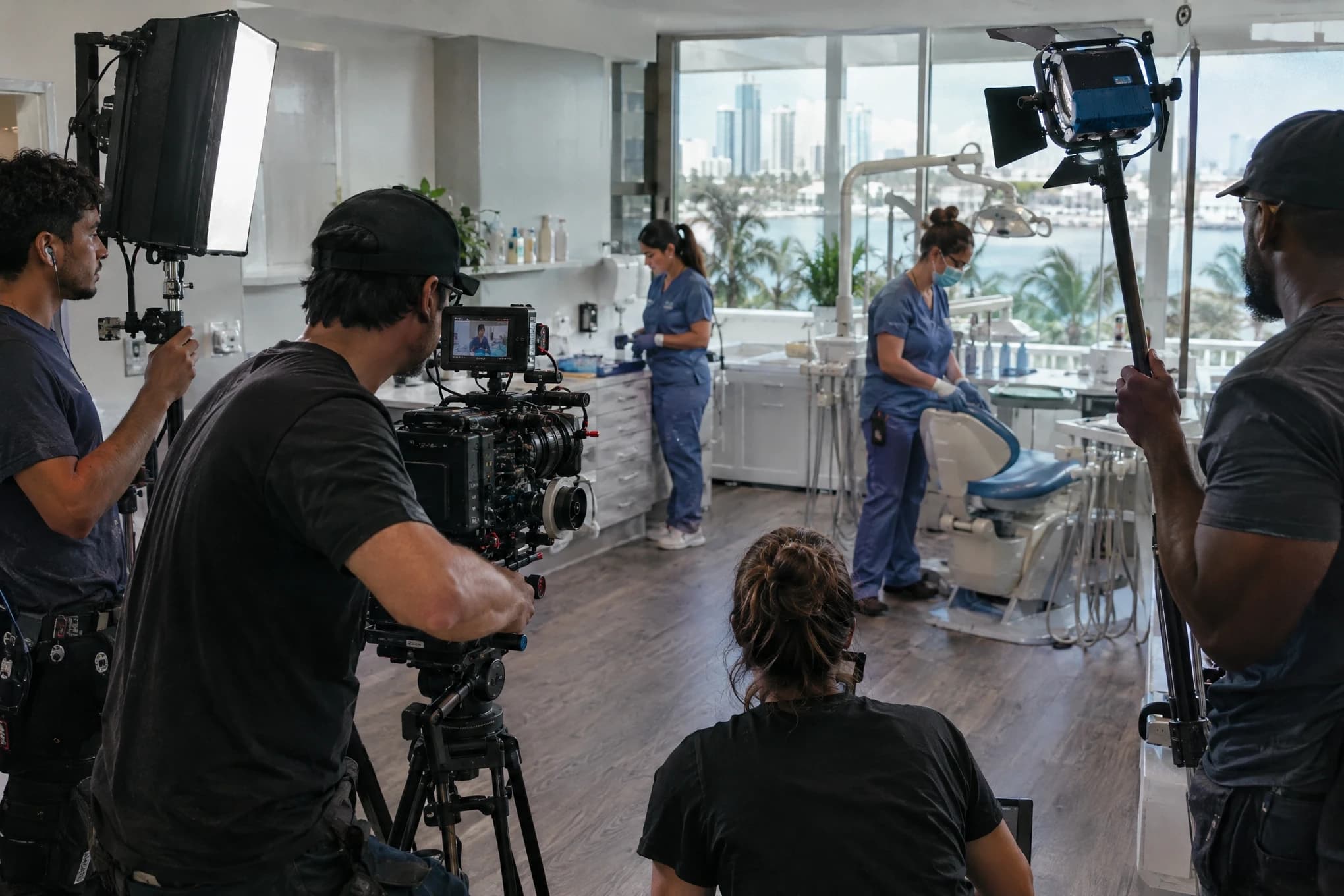 Un equipo de rodaje de cinco personas graba con cámara de cine y luces dentro de una clínica dental grande