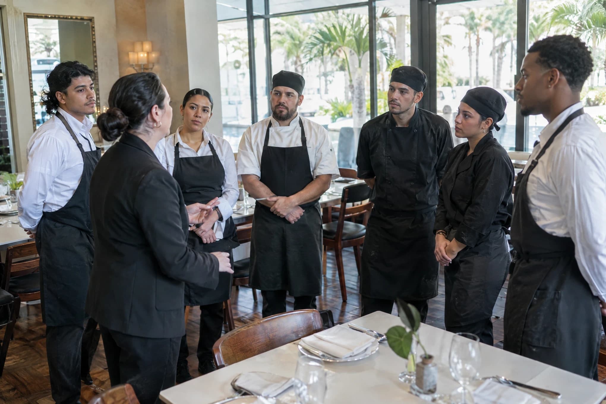 El gerente de un restaurante reúne a siete meseros y cocineros antes del servicio