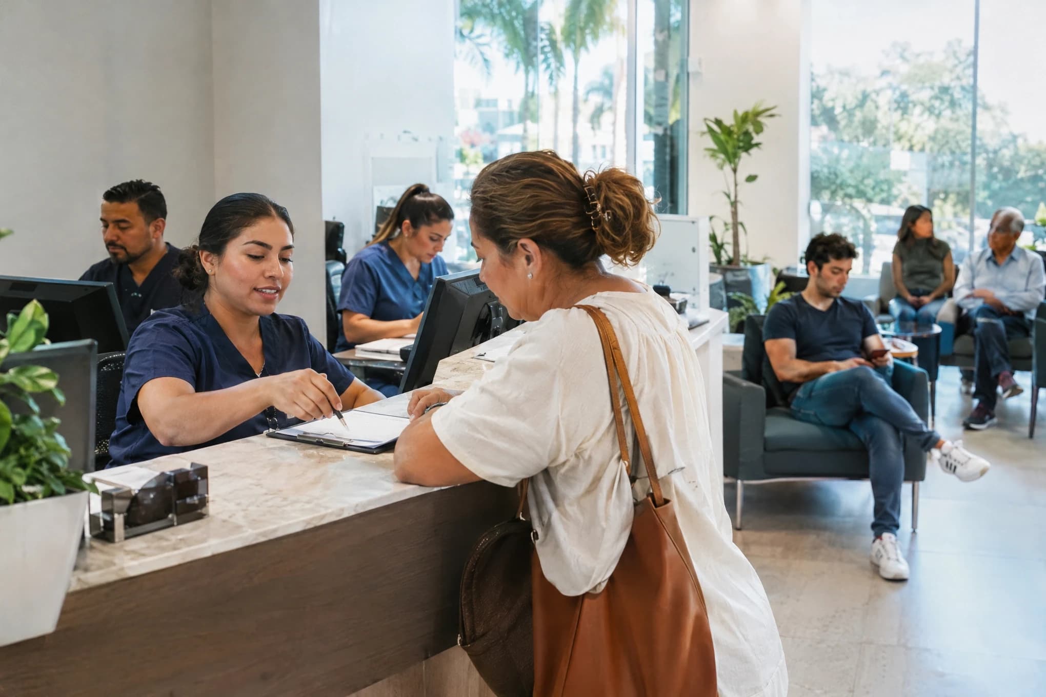 En la recepción de una clínica médica, el personal atiende a pacientes que se registran mientras otros esperan