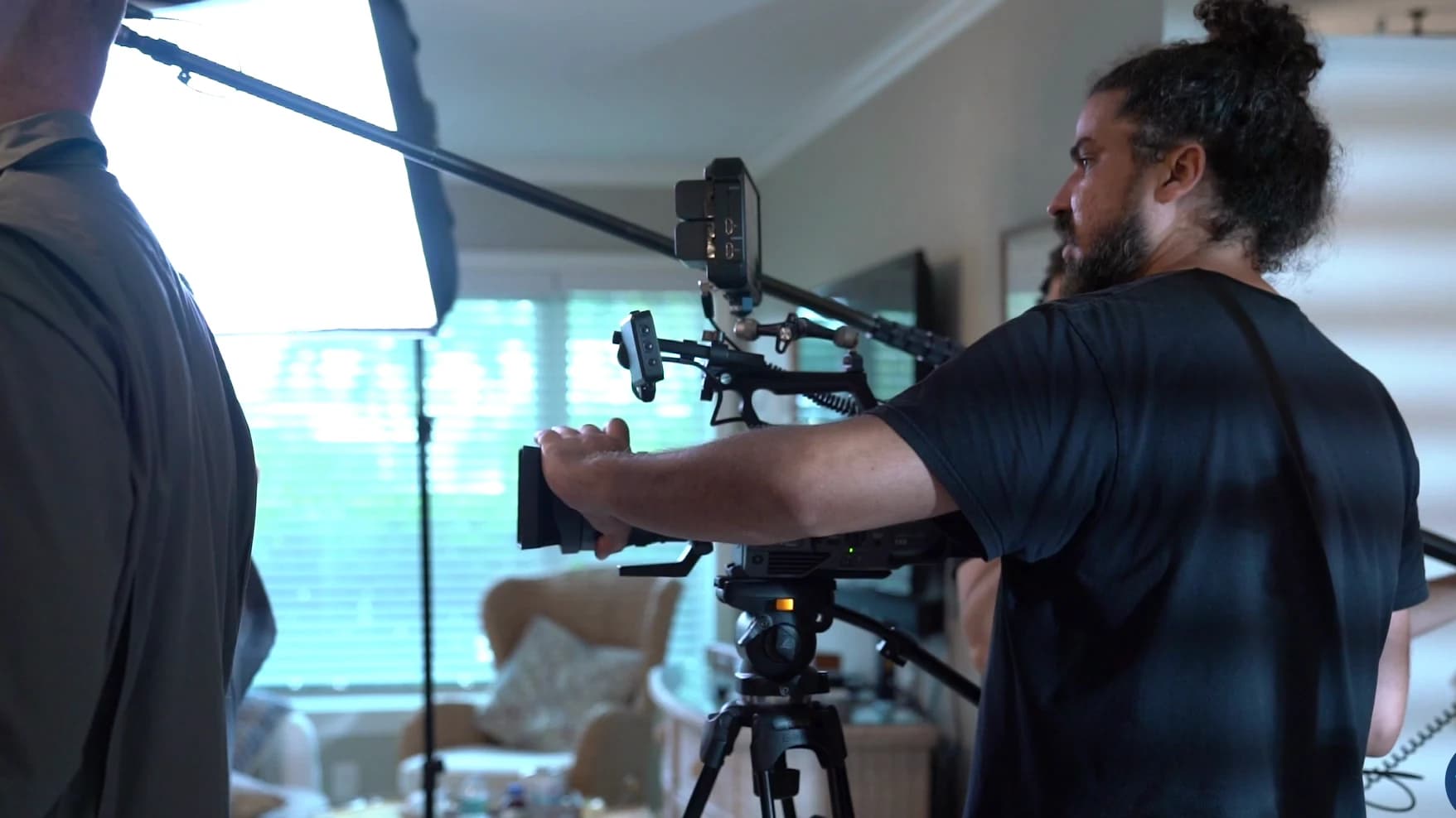 Un camarógrafo de Brito Marketing opera la cámara de cine en trípode, con luz suave, en un rodaje en interior.