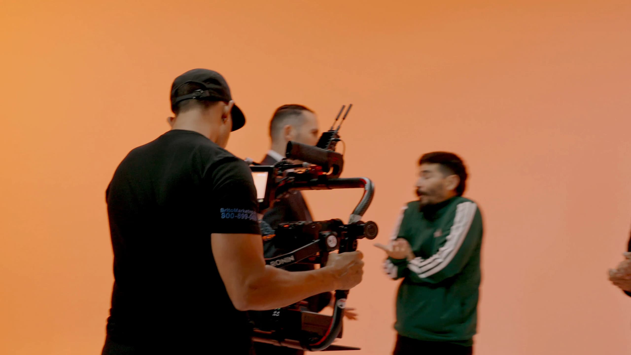 Un camarógrafo de Brito Marketing graba con gimbal frente a un fondo de color en un rodaje en estudio.